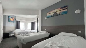 Ein Hotelzimmer mit drei Betten, einem großen Fenster mit Vorhängen, einem Bild an der Wand und einem modernen Design.