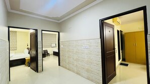 Een hotelgang met een spiegelwand, een houten deur en een betegelde vloer.