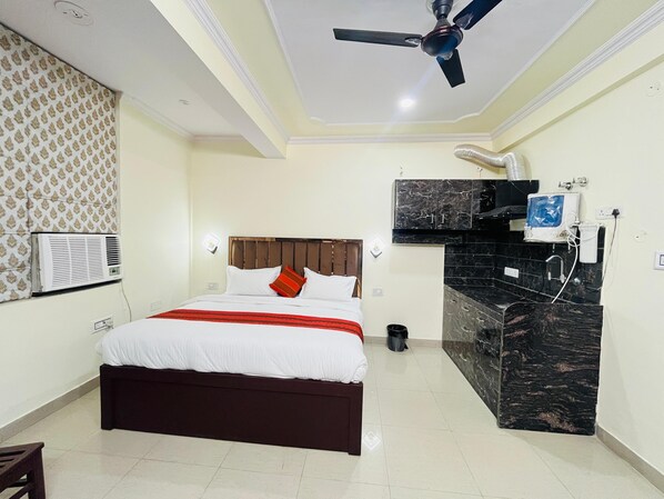A hotel room with a bed, a ceiling fan, a built-in TV, a marble countertop, and an air conditioning unit. - Hotel Silver Stay 04 (Jaipur)