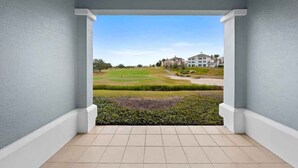 A balcony with a view of a golf course and buildings in the distance. - First Floor Condo with Golf Course Views (Kissimmee)