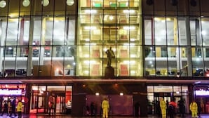 The exterior of Manchester United stadium with a large illuminated sign, glass facade, and a statue in front. - Stylish Spacious 1Bd Apt-kingbed-10min Heaton Park (Manchester)