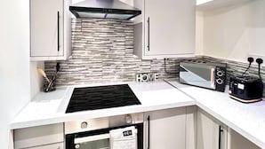 A modern kitchen with a built-in stove, oven, and microwave. There are cabinets and a countertop with a toaster. - Stylish Spacious 1Bd Apt-kingbed-10min Heaton Park (Manchester)