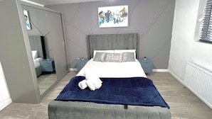 A modern bedroom with a large bed, a mirror, a bedside table, and a painting on the wall. - Stylish Spacious 1Bd Apt-kingbed-10min Heaton Park (Manchester)
