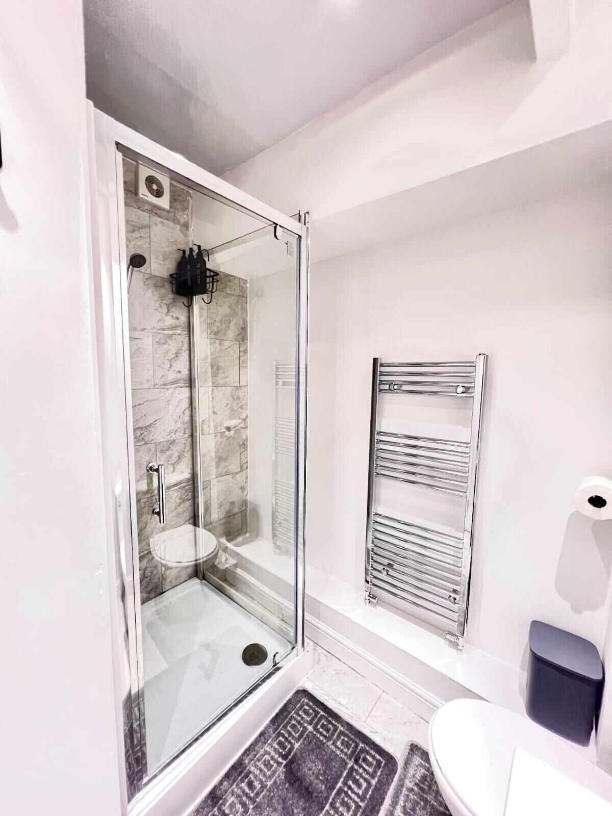 Un bagno moderno con cabina doccia in vetro, lavandino bianco e porta asciugamani.