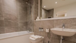 Et moderne badeværelse med badekar, toilet og håndvask.