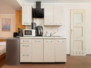 A compact kitchenette with a microwave, coffee maker, and sink.