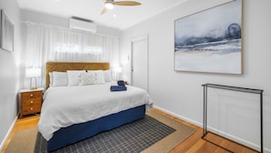 Een hotelkamer met een bed, plafondventilator, schilderij en radiator.