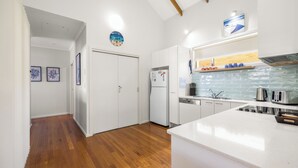 Een moderne keuken met witte kasten, een inbouw vaatwasser en een wit aanrecht.