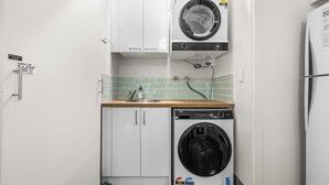 Een kleine keuken met een wasmachine, vaatwasser en een koelkast.