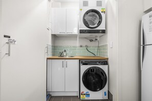 Une cuisine compacte équipée d’un lave-linge, d’un lave-vaisselle et d’un réfrigérateur.