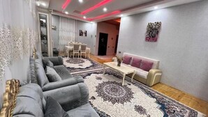 A modern living room with a grey sofa, a white coffee table, and a patterned rug. - Gabala Dreams, charming 2 bedroom villa, (Vandam)