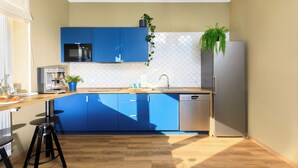 Une cuisine moderne avec des meubles bleus, un réfrigérateur en acier inoxydable, un four à micro-ondes et une machine à café.