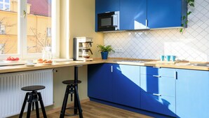 Une cuisine moderne avec des meubles bleus, un four à micro-ondes et une fenêtre donnant sur des immeubles.
