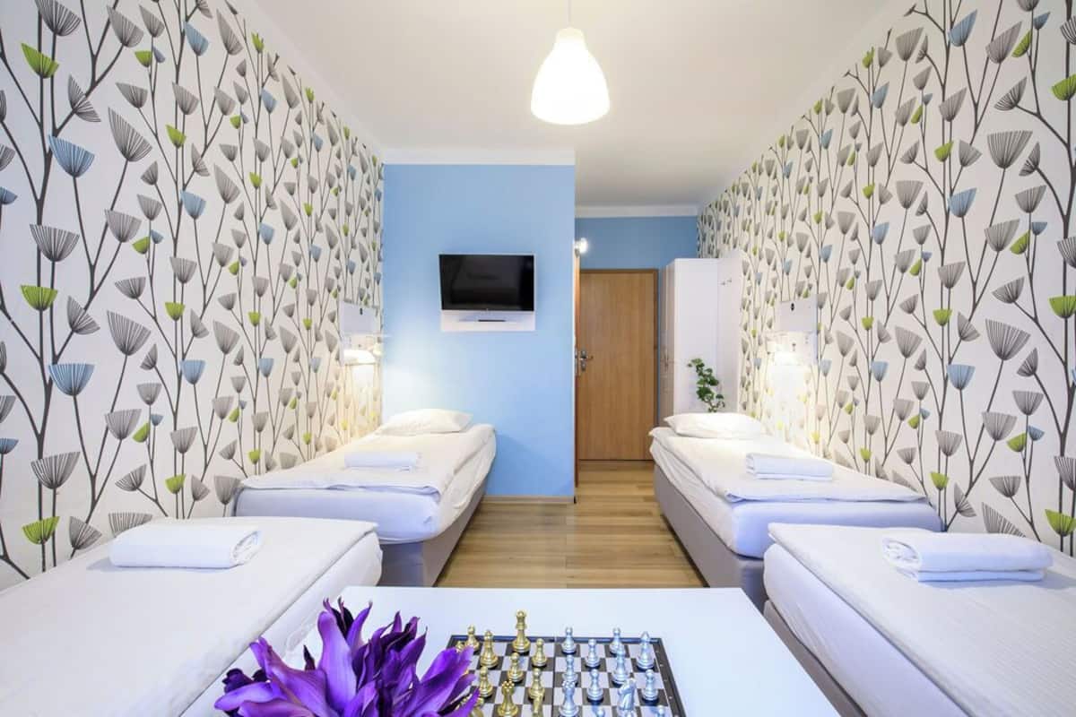 Ein Hotelzimmer mit zwei Betten, einem an der Wand montierten Fernseher und einem Schachbrett auf dem Tisch.