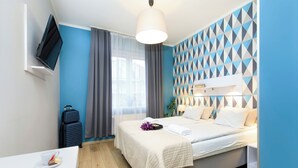 Une chambre d’hôtel moderne équipée d’un lit, d’une table de chevet et d’un téléviseur fixé au mur.