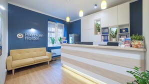 Un espace d’accueil comprenant un canapé, un comptoir et un panneau indiquant « Auberge de jeunesse de qualité supérieure ».