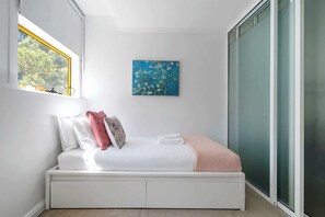 A modern bedroom with a bed, pillows, a blanket, a window, and a painting on the wall. - Idyllic and Spacious apartment near Trendy Zetland (Waterloo)
