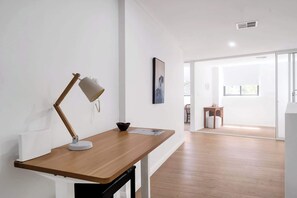 A modern room with a wooden desk, a desk lamp, a framed picture, and a window. - Idyllic and Spacious apartment near Trendy Zetland (Waterloo)