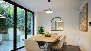 A dining area with a large table, chairs, a potted plant, and a mirror on the wall.