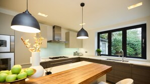 Una cocina moderna con una isla central, iluminación colgante y vistas a zonas verdes.
