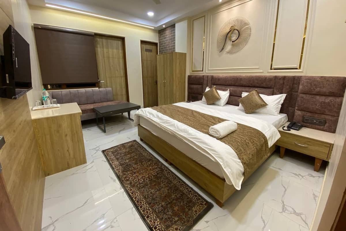 Une chambre d’hôtel moderne dotée d’un grand lit, d’un coin salon avec un canapé, d’un bureau et d’une télévision.