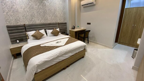 Een moderne slaapkamer met een groot bed, een bureau en een airconditioner aan de muur.