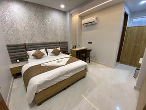 A modern bedroom with a large bed, a desk, and an air conditioning unit on the wall. - Hotel liyan inn (Kanpur)