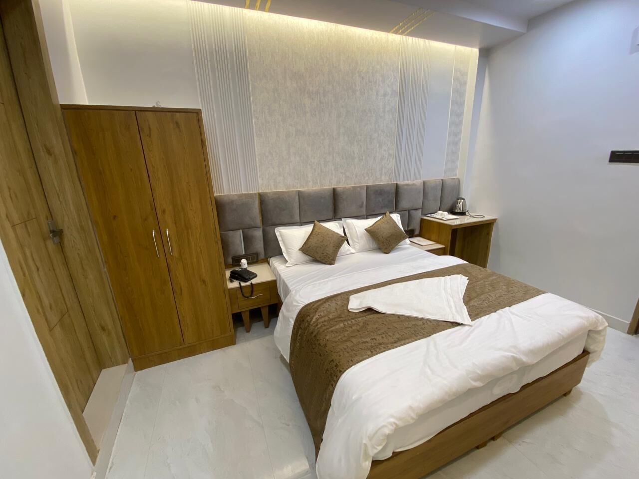Ein modernes Schlafzimmer mit einem großen Bett, einem Holzschrank, Nachttischen und einer neutralen Farbgestaltung.