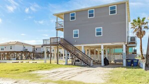 A two-story building with a balcony, a staircase, and a covered outdoor area. - Surfside Beach Getaway Steps from the Ocean (Surfside Beach)