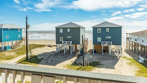 A beachfront property with two elevated houses, a sandy beach, and a clear sky. - Surfside Beach Getaway Steps from the Ocean (Surfside Beach)