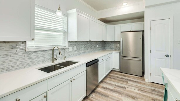 A modern kitchen with white cabinetry, a stainless steel refrigerator, and a dishwasher. - Family Beach Getaway with Ocean Views (Surfside Beach)
