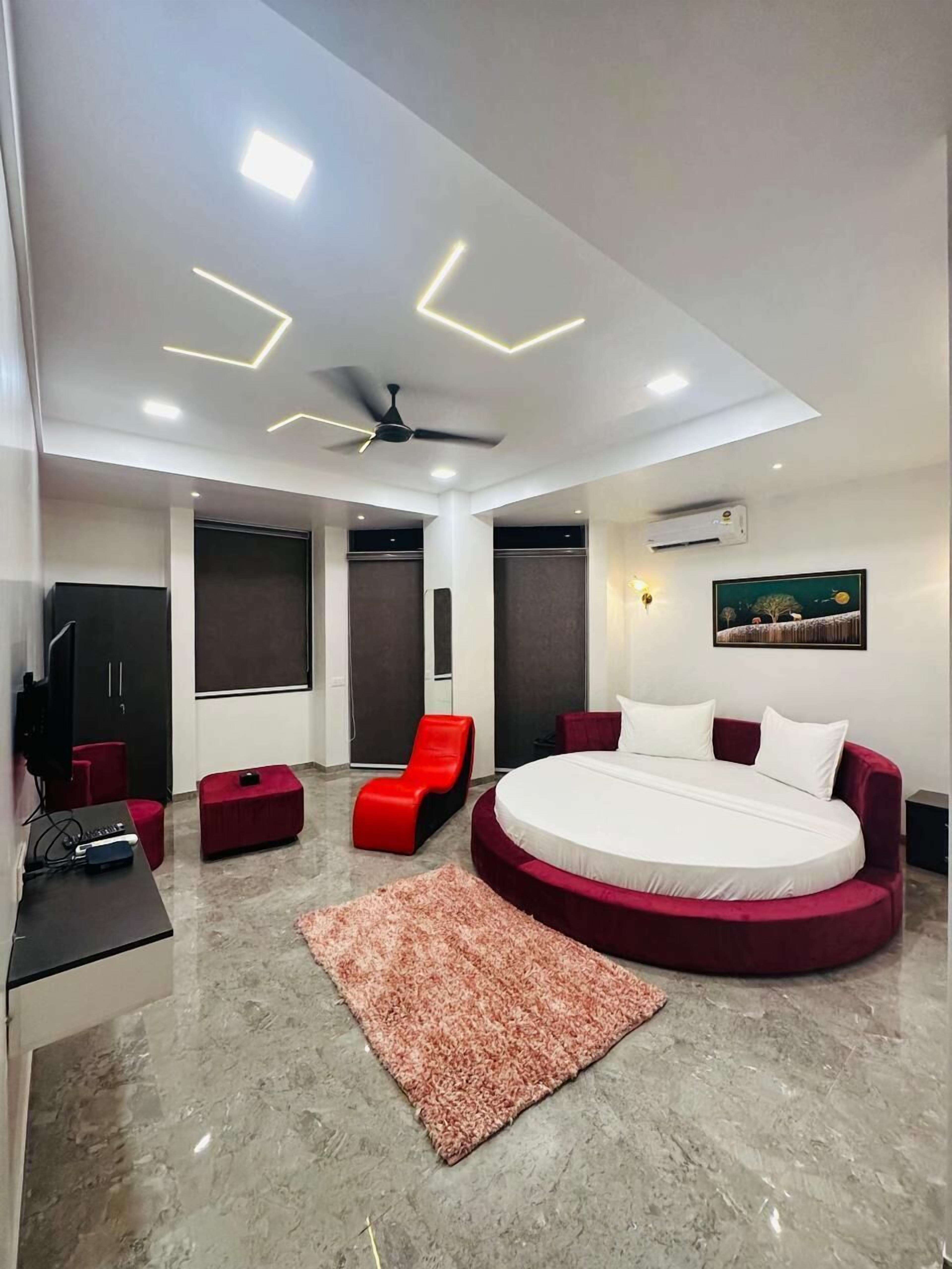 Une chambre moderne avec un lit rond, un ventilateur de plafond et un fauteuil rouge.