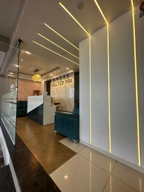 A modern hotel lobby with a reception desk, a chandelier, and a sofa. - Hotel Hill Top Inn  (Pune)