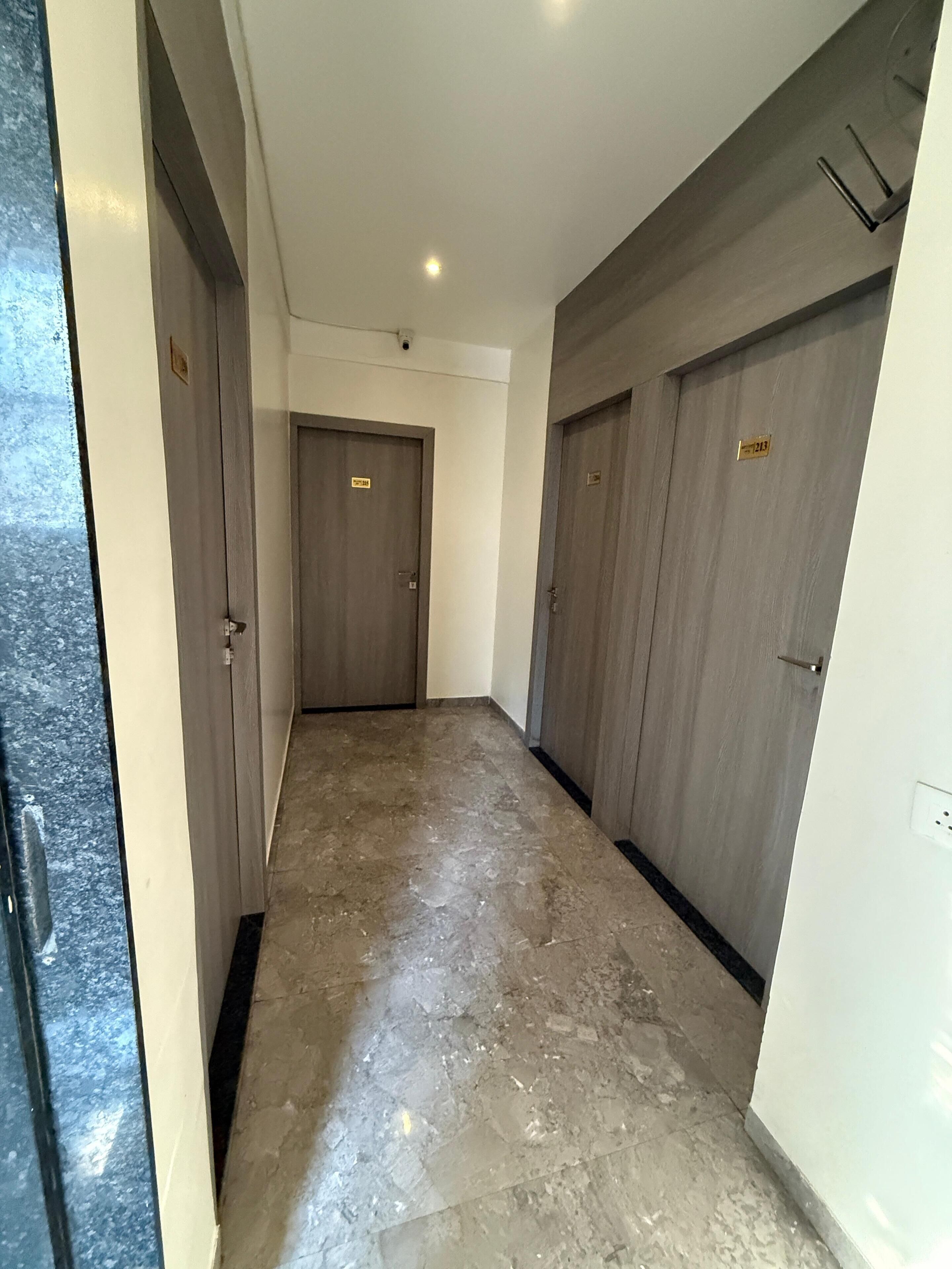 A hallway with two doors, each marked with a number plate. The floor is tiled, and the walls are painted white.