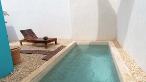 A small pool with a wooden lounge chair and a potted plant. - Charming Tulum House with Private Pool and Bikes (Tulum)
