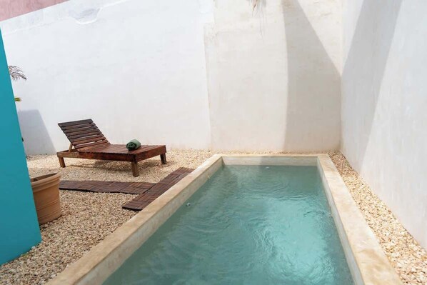 A small pool with a wooden lounge chair and a potted plant. - Charming Tulum House with Private Pool and Bikes (Tulum)
