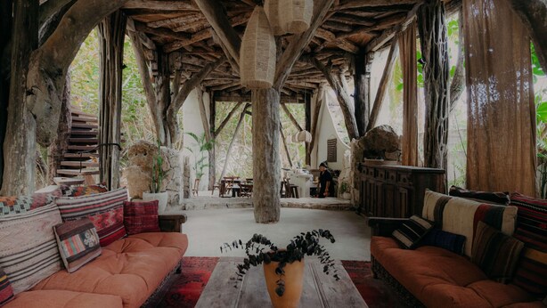 A rustic wooden interior with a central seating area, a wooden table, and a large potted plant. - Charming Tulum House with Private Pool and Bikes (Tulum)