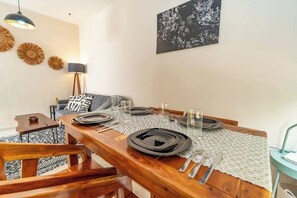 Uma sala de jantar com uma mesa de madeira posta para quatro pessoas, rodeada por cadeiras.