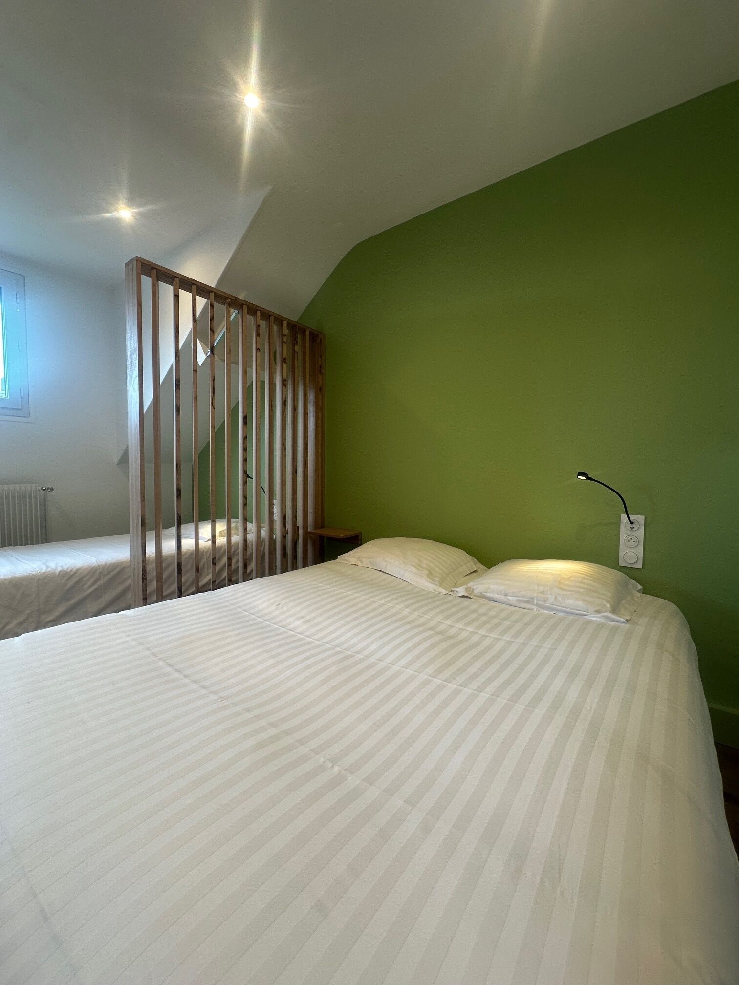 Una camera da letto con un letto grande, una parete divisoria in legno e una parete verde.