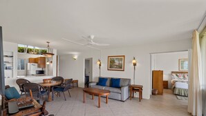 A spacious living area with a sofa, chairs, a dining table, and a kitchen in the background. - Menehune Shores, #118^ 3 Bedroom Condo (Kihei)