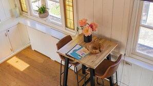 A wooden dining table with a vase of flowers, two chairs, and a window with a view of the outdoors. - Pat's Home, sleeping under the stars. (Alkmaar)