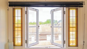 A room with a large window featuring two open doors, each with a yellow-tinted glass panel. - Pat's Home, sleeping under the stars. (Alkmaar)