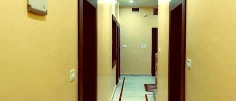 A hotel hallway with a light blue carpet and red stripes, leading to a door at the end.