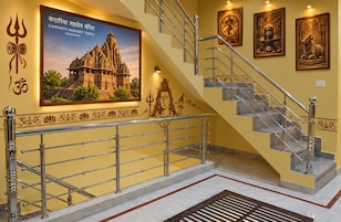 Uma escadaria com corrimãos de metal e piso de mármore, que leva a um templo com um cartaz grande e decorações nas paredes.