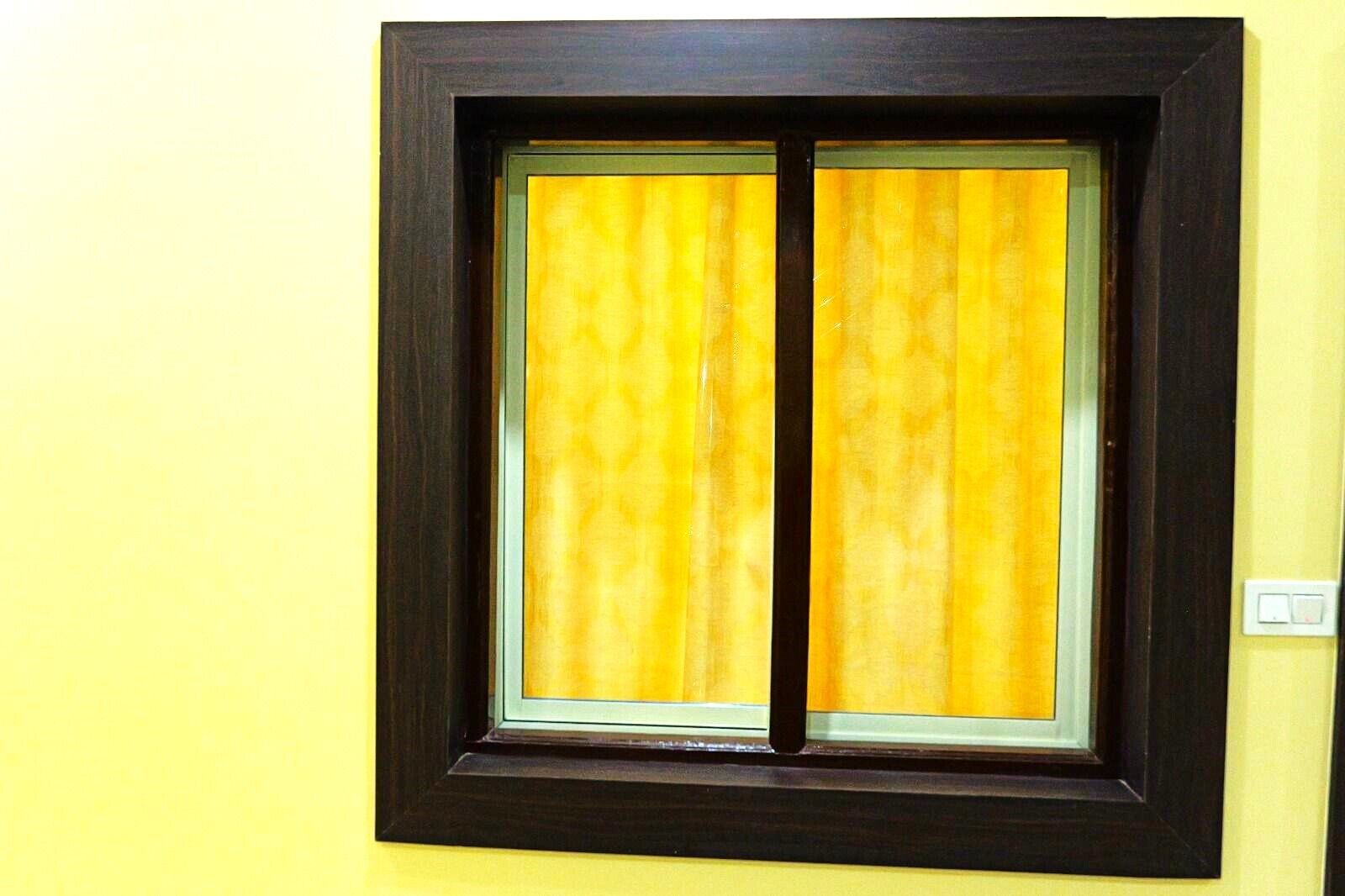 Una ventana con marco oscuro y cortinas amarillas.