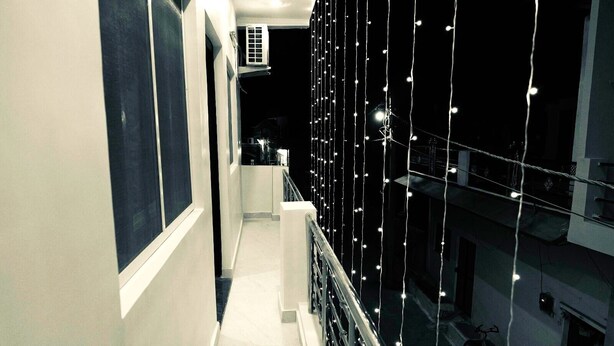 A narrow corridor with a balcony on the right, decorated with string lights. - Hotel The Ram Krishna (Rajnagar)
