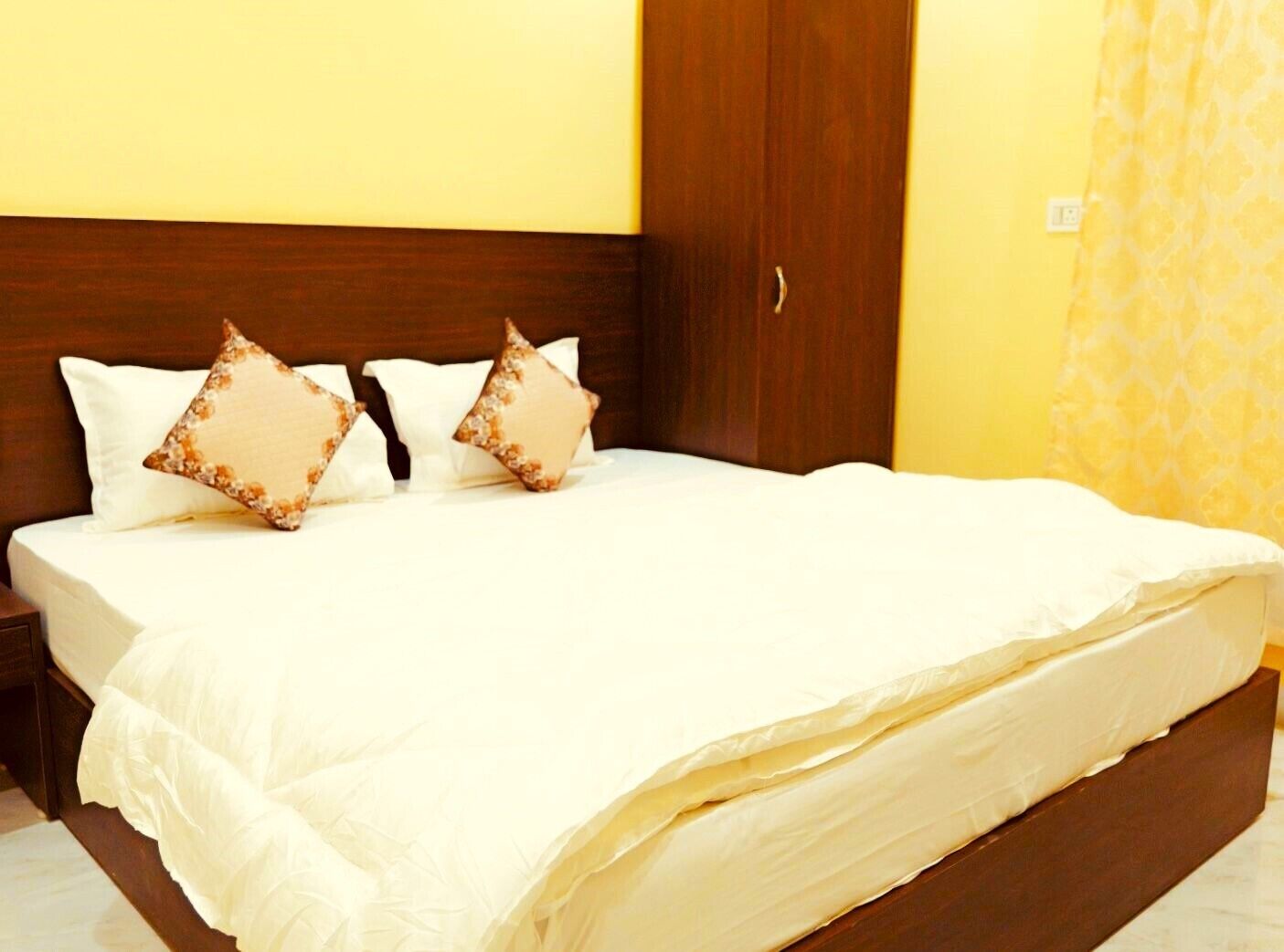 Una cama bien hecha con ropa de cama blanca y dos almohadas decorativas.
