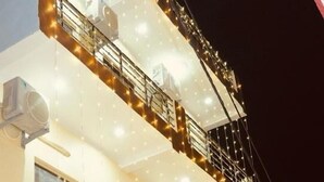 A multi-story building with balconies, air conditioning units, and a red carpet leading to the entrance. - Hotel The Ram Krishna (Rajnagar)