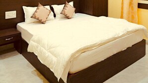 A hotel room with a bed, a wardrobe, a ceiling fan, an air conditioning unit, and a window with curtains. - Hotel The Ram Krishna (Rajnagar)