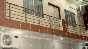 A multi-story building with air conditioning units, a signboard for Ram Krishna Home Stay, and a red carpet leading to the entrance. - Hotel The Ram Krishna (Rajnagar)